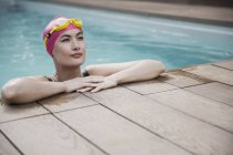 Mujer segura en gorra de natación y gafas apoyadas en el borde de la piscina - foto de stock
