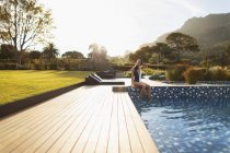 Young woman in bathing suit relaxing at sunny, luxury swimming pool, Cape Town, South Africa — Stock Photo