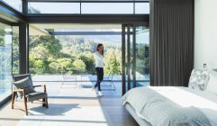 Frau telefoniert in Terrassentür des modernen Luxus-Schlafzimmers — Stockfoto