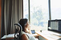 Donna d'affari con auricolare che lavora al computer nel soleggiato home office — Foto stock
