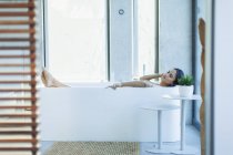Heitere Frau entspannt sich in moderner Badewanne — Stockfoto