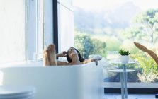 Heitere Frau entspannt sich in Badewanne im modernen Badezimmer — Stockfoto