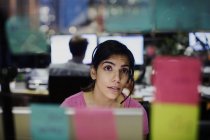 Geschäftsfrau mit Headset blickt auf Klebezettel, Planung im Büro — Stockfoto