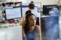 Empresária focada com fones de ouvido trabalhando no computador no escritório — Fotografia de Stock