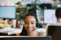 Retrato mujer de negocios confiada con auriculares en la computadora en la oficina - foto de stock