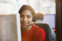 Portrait smiling, confident businesswoman with headset working at computer in office — Stock Photo