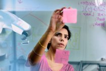 Planejamento do engenheiro feminino focado, usando notas adesivas no escritório — Fotografia de Stock