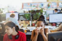 Бізнес-леді з алергією чхає в тканину в офісі — стокове фото