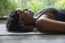 Jovem mulher serena que põe na posição do cadáver na esteira do yoga — Fotografia de Stock