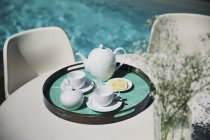 Teeservice auf sonnigem Terrassentisch am Pool — Stockfoto