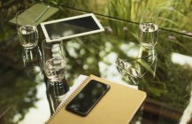 Смартфон і блокнот на столі з водяними окулярами — стокове фото