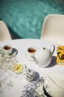 Serviço de chá na mesa de pátio ensolarada à beira da piscina de verão — Fotografia de Stock