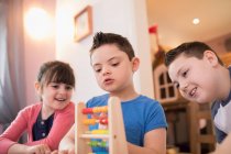 Junge mit Down-Syndrom und Geschwister spielen mit Spielzeug — Stockfoto