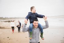 Glücklicher Vater trägt Sohn mit Down-Syndrom am Strand — Stockfoto