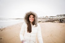 Portrait happy carefree teenage girl in fur jacket on ocean beach — Stock Photo