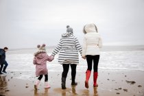 Famille en vêtements chauds marchant sur la plage de l'océan d'hiver — Photo de stock