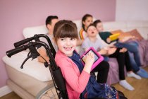 Счастливая девочка-инвалид в инвалидной коляске с помощью цифрового планшета — стоковое фото