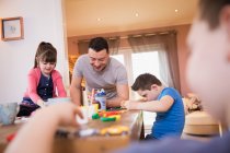Glücklicher Vater spielt mit Down-Syndrom-Kindern am Esstisch — Stockfoto