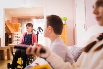 Щаслива дівчина в інвалідному візку з братами вдома — стокове фото