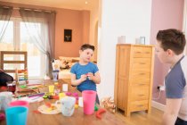 Junge mit Down-Syndrom spielt mit Spielzeug am Esstisch — Stockfoto