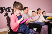 Дівчина з синдромом Дауна в інвалідному візку за допомогою цифрового планшета — стокове фото