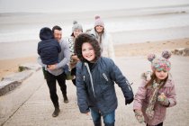 Familia feliz en ropa de abrigo caminando por la rampa de playa - foto de stock