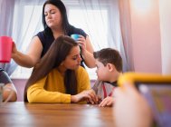 Мальчик с синдромом Дауна разговаривает с сестрой за обеденным столом — стоковое фото