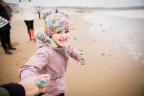 Retrato feliz chica despreocupada en ropa de abrigo corriendo en la playa de invierno - foto de stock