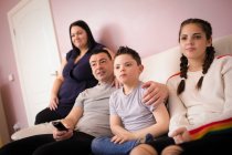 Familia con síndrome de Down hijo viendo la televisión en el sofá de la sala de estar - foto de stock