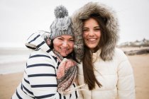 Portrait happy mother and daughter in warm clothing on beach — Stock Photo