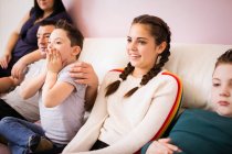 Счастливая семья смотрит телевизор на диване гостиной — стоковое фото