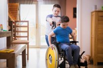 Menino empurrando irmão com síndrome de Down em cadeira de rodas — Fotografia de Stock