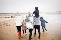 Família em roupas quentes andando na praia do oceano de inverno — Fotografia de Stock