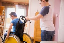 Ragazzo spingendo fratello in sedia a rotelle — Foto stock