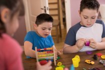 Мальчик с синдромом Дауна и брат играют с игрушками за столом — стоковое фото