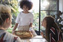 Mulher nova que serve pizza caseira para amigos na mesa de jantar — Fotografia de Stock