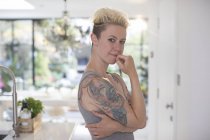 Retrato mulher confiante com tatuagens na cozinha — Fotografia de Stock