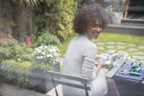Portrait smiling young woman using smart phone on patio — Stock Photo