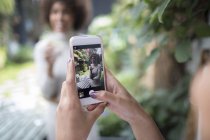 Личная перспективная женщина со смартфоном фотографирует подругу — стоковое фото