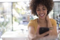Грайлива щаслива молода жінка бере селфі з телефоном — стокове фото