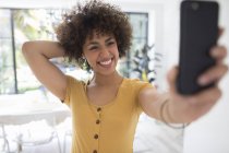Счастливая уверенная в себе молодая женщина делает селфи со смартфоном — стоковое фото