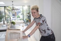 Портрет счастливой женщины-фрилансера, работающей за ноутбуком на кухне — стоковое фото