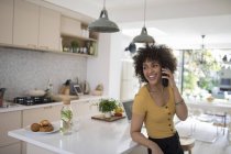Felice giovane donna parlando su smart phone in cucina — Foto stock