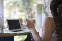 Junge Frau trinkt Tee am Laptop im Home Office — Stockfoto