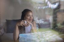 Продумана молода жінка п'є каву в ноутбуці у вікні — стокове фото