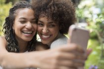 Happy playful young women friends taking selfie with camera phone — Stock Photo