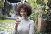 Portrait happy young woman drinking water on patio — Stock Photo
