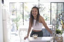 Happy young woman laughing in kitchen — Stock Photo