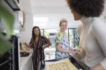 Happy young women friends cooking in kitchen — Stock Photo