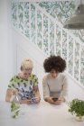 Giovani amici donne che utilizzano smartphone in cucina — Foto stock